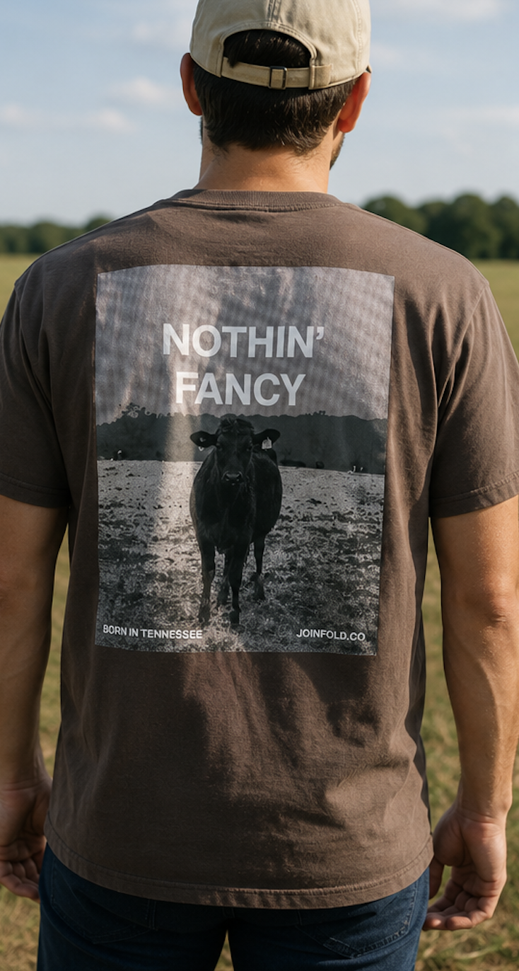 Back of the tee worn by a model, showing the "Nothin' Fancy" cow graphic in a Tennessee field
